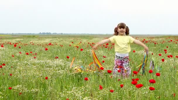 šťastná holčička mává s barevnými stuhami na louce - Záběry, video