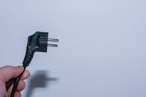 plug realizada oblíqua em uma mão salvar eletricidade vista esquerda com fundo cinza - Foto, Imagem