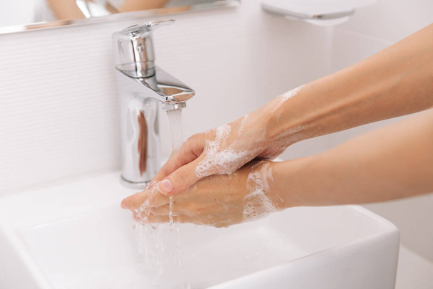 Washing hands under the flowing water tap. Washing hands rubbing with soap for corona virus prevention, hygiene to stop spreading corona virus in or public wash room. Hygiene concept hand detail - Zdjęcie, obraz