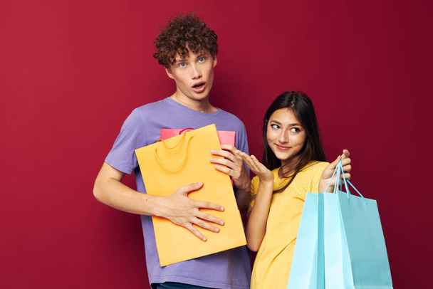 portrait of a man and a woman colorful bags shopping fun red background unaltered - Photo, image