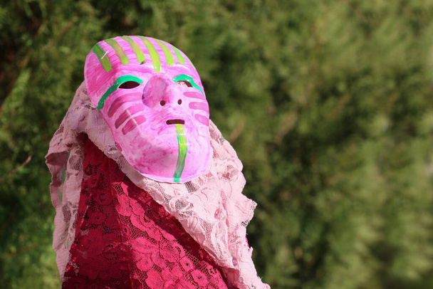 Барвиста маска театральної маски-арккіна, знята надворі з шарфами навколо неї
  - Фото, зображення