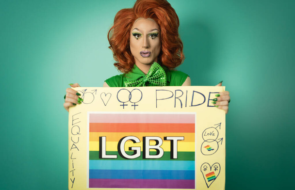 Drag queen celebrating gay pride holding banner with rainbow flag - LGBTQ social community concept - Fotó, kép
