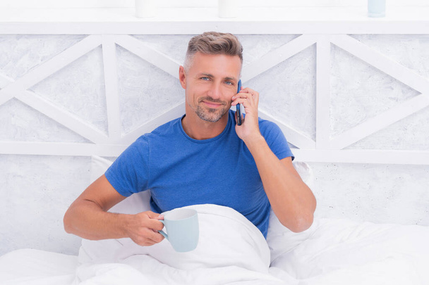 Starting day with a call. Happy guy talk on phone in bed. Keeping in touch through call. - Fotoğraf, Görsel