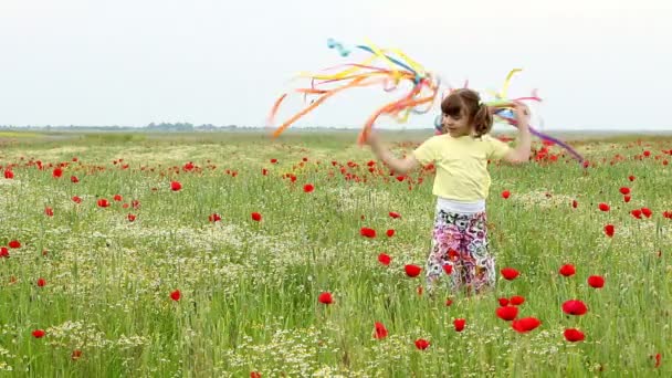 holčička mává s barevnými stuhami na louce - Záběry, video