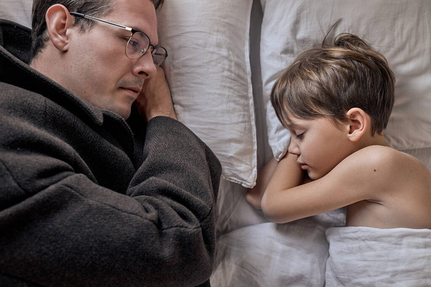 Father come to say goodbye to child boy before leave for work in morning, on bed - Photo, Image