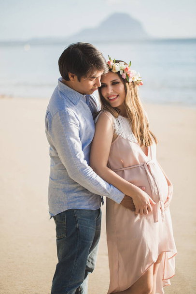 Beautiful pregnant girl and man on the beach. - Фото, зображення