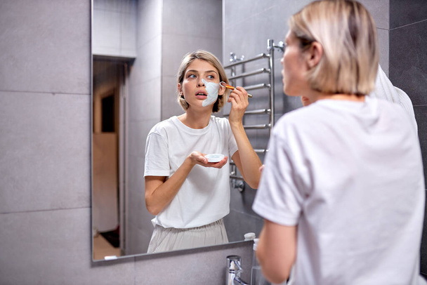 Young beautiful woman using skin face cream moisturizing lotion after taking bath - Fotografie, Obrázek