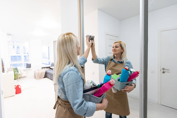 Молода красива жінка прибирає дзеркало. Служба прибирання. Прибирання вдома
 - Фото, зображення