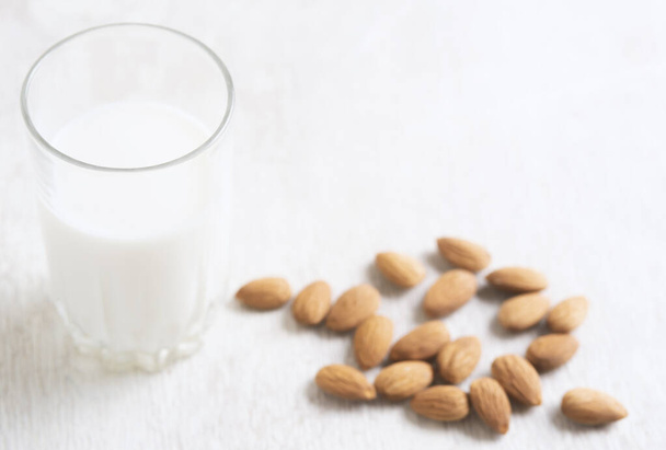 Vegan dairy free almond milk and almonds on white wooden background. Selective focus, space for text. - Φωτογραφία, εικόνα