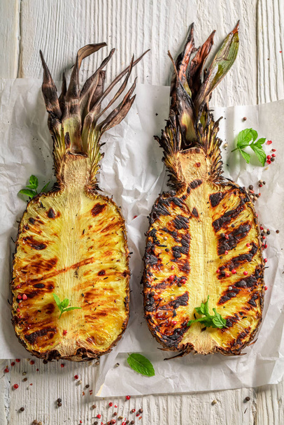 Sweet roasted pineapple with herbs and pepper. Grilled ananas on grate with fire. - Foto, afbeelding