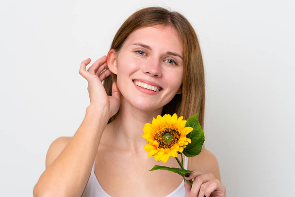 Young English woman holding a sunflower while smiling. Close up portrait - Φωτογραφία, εικόνα