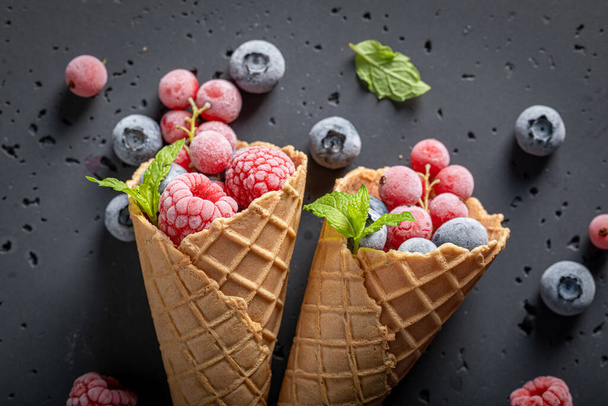 Cold ice cream with frozen berries in cone. Frozen fruit in a cone as a sorbet. - Foto, Bild