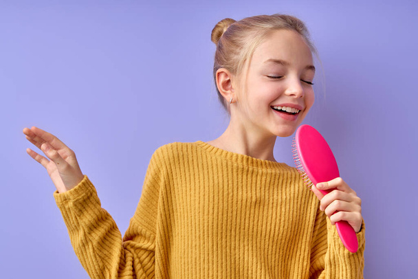 little teenage American girl sing in toy hairbrush microphone, funny small artistic kid - Foto, Imagen