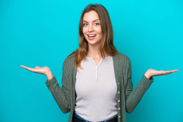 Young caucasian woman isolated on blue background with shocked facial expression - Φωτογραφία, εικόνα