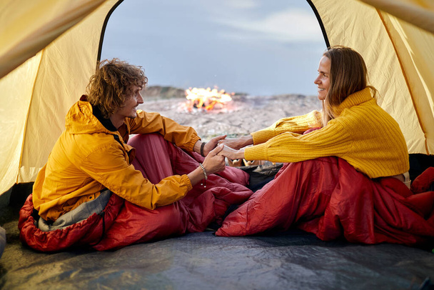 Adorable couple sit inside of tent talking, man and woman in love, in nature - Foto, Imagem