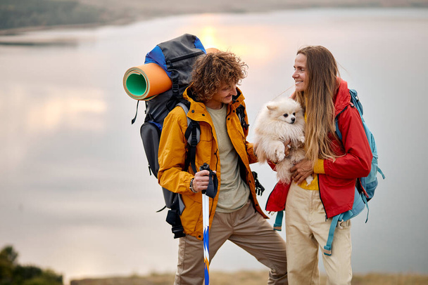 gyönyörű pár játszani Spitz kutya élvezze a tó táj a háttérben, utazás - Fotó, kép