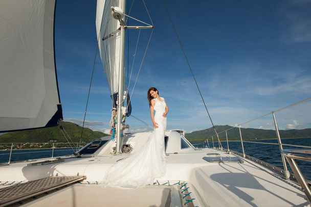 Happy bride on a yacht. White yacht with sail set goes along the island. - Fotografie, Obrázek
