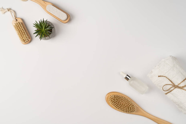 Flat lay, a set of bath products. Eco-friendly wooden brush, clean fresh towel and oil serum for face and body on a white background. - Foto, Imagem