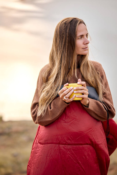 Beautiful female holding cup of tea in hands standing in contemplation of nature - Foto, afbeelding