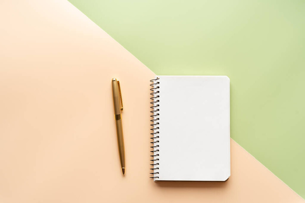 Hintergrund aus zwei Farben, hellgrün und pfirsich. Draufsicht, Tapete. Notizbuch und goldener Stift. - Foto, Bild