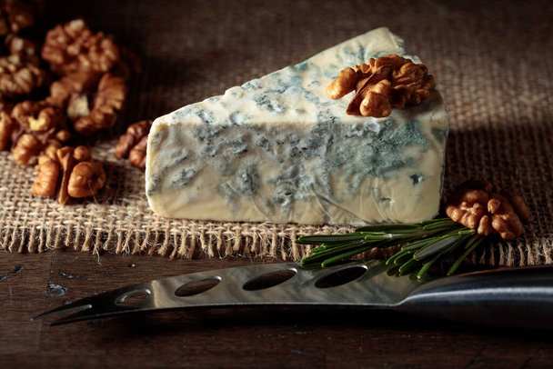Blue cheese with walnuts and rosemary on an old wooden table. - 写真・画像