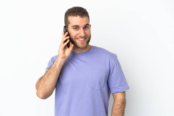 Giovane uomo caucasico bello isolato su sfondo bianco mantenendo una conversazione con il telefono cellulare con qualcuno - Foto, immagini