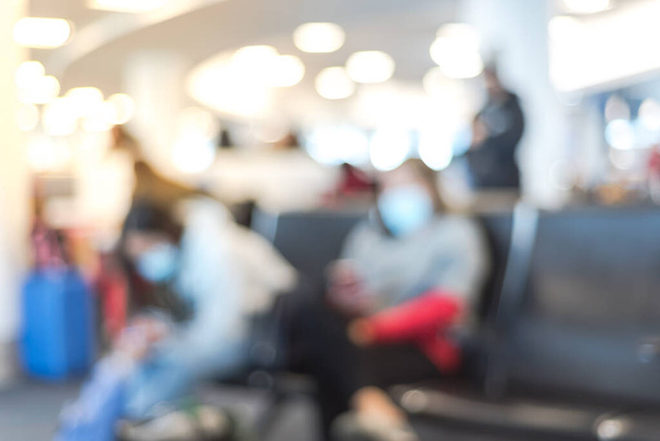 Imagem turva do passageiro em máscaras esperando no portão do terminal no aeroporto de Los Angeles, Califórnia, EUA. Viajantes sentados em poltrona com medidas de segurança para a pandemia do coronavírus covid-19 - Foto, Imagem
