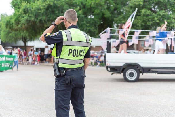 Achteraanzicht van politieagent op openbaar 4 juli parade street event in de buurt van Dallas, Texas, Amerika. Rechtshandhaving en bewaker op live festival evenement. - Foto, afbeelding