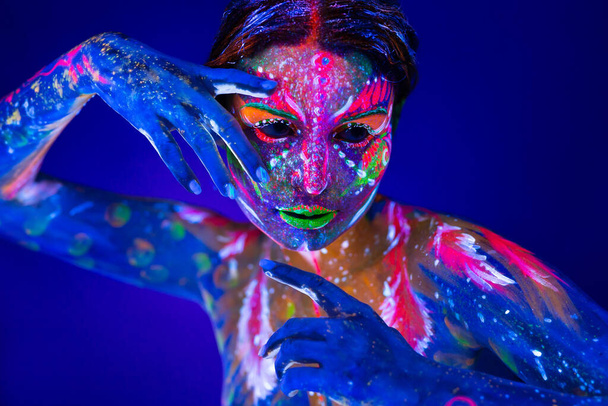 Body art glowing in ultraviolet light. Body art on the body and hand of a girl glowing in the ultraviolet light. - Photo, Image