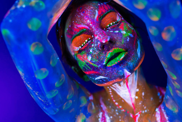 Body art glowing in ultraviolet light. Body art on the body and hand of a girl glowing in the ultraviolet light. - Photo, image