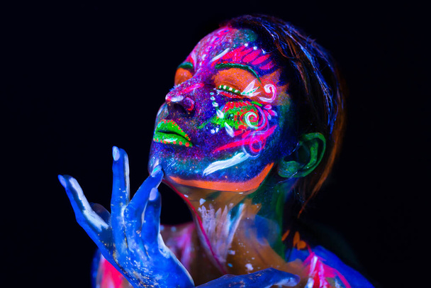Body art glowing in ultraviolet light. Body art on the body and hand of a girl glowing in the ultraviolet light. - Photo, Image