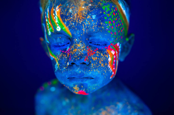 Portrait of a neon child boy posing in UV. - Foto, afbeelding