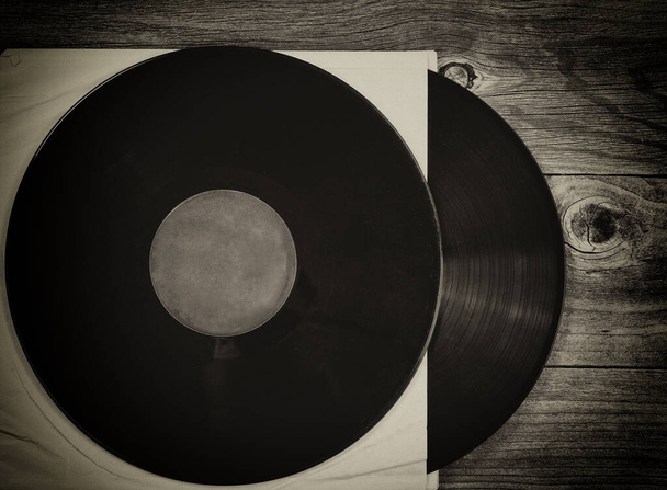 Empilement de disques de musique anciens dans des supports de papier originaux sur une table en bois vieilli avec effet vintage - Photo, image