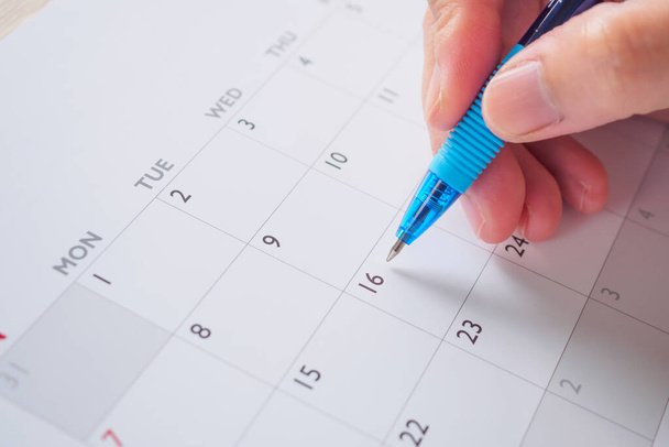 Kobieta ręka z piórem pisanie na dzień kalendarzowy biznes planowanie spotkania koncepcja - Zdjęcie, obraz