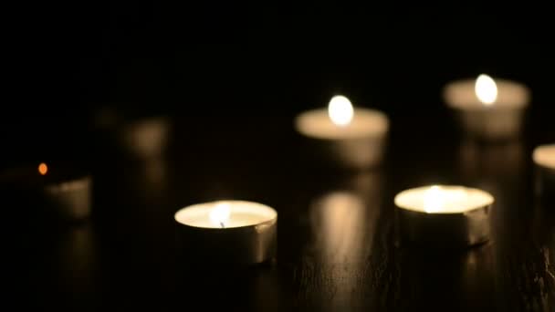 Muitas pequenas velas flamejantes na mesa preta
 - Filmagem, Vídeo