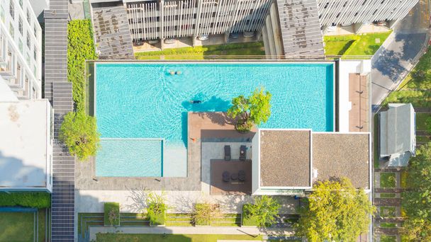 Aerial view of swimming pool on rooftop of hotel apartment building in Bangkok downtown skyline, urban city view. Relaxing in summer season in travel holiday vacation concept. Recreation lifestyle. - Фото, зображення