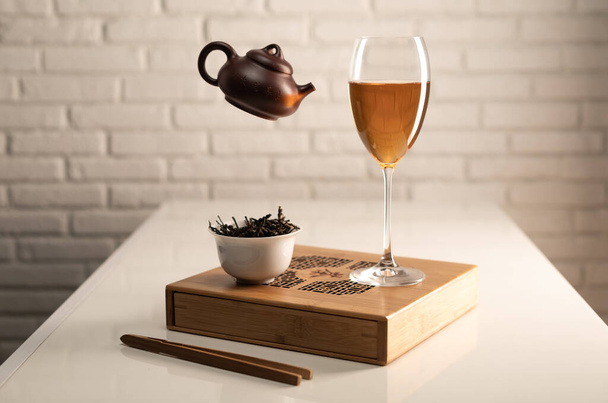 table à thé avec appareils électroménagers et un verre à vin dans lequel le thé est infusé - Photo, image