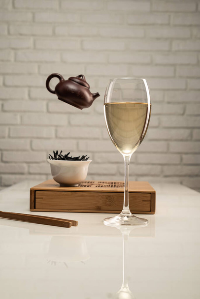 mesa de té con electrodomésticos y una copa de vino en la que se elabora el té - Foto, Imagen