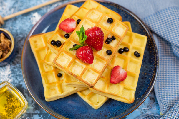 sweet dessert Belgian waffles with strawberries and blueberries on a plate with honey - Фото, зображення