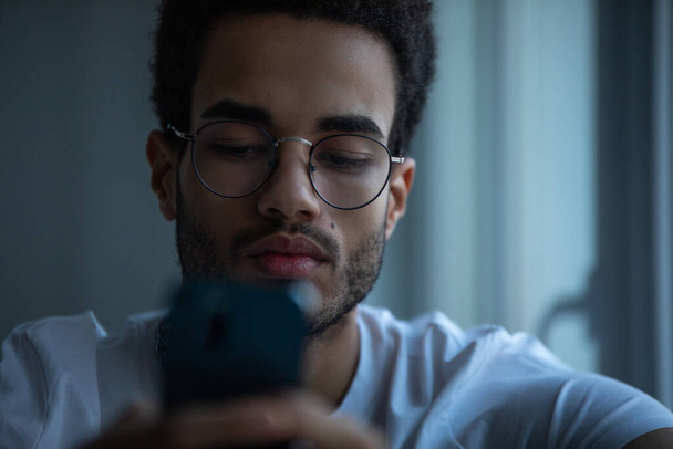 Portrait of an african american man in glasses using a smartphone. - Zdjęcie, obraz