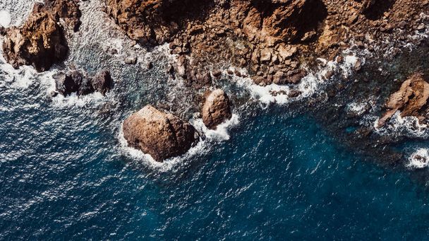 Sopra vista verticale di acqua blu e costa rocciosa. Natura paesaggio marino da drone. Sopra il mare con onde e acqua pulita trasparente - Foto, immagini