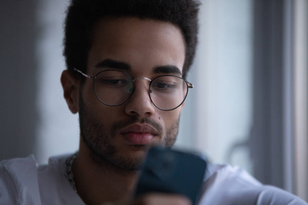 Portrait of an african american man in glasses using a smartphone. - Foto, afbeelding