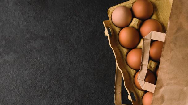 エコパッケージの自然な新鮮な鶏の卵は、暗いキッチンテーブルの上にピンをローリング。最上階だ。平置きだ。民俗スタイル。スペースのコピー - 写真・画像