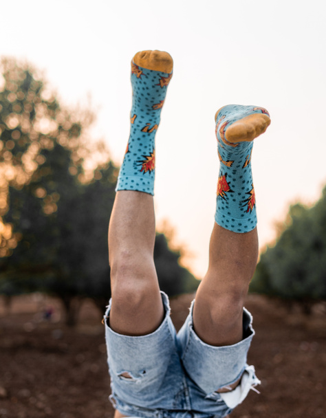 Man's legs up in the air with colourful socks and blue jeans short. - Photo, Image