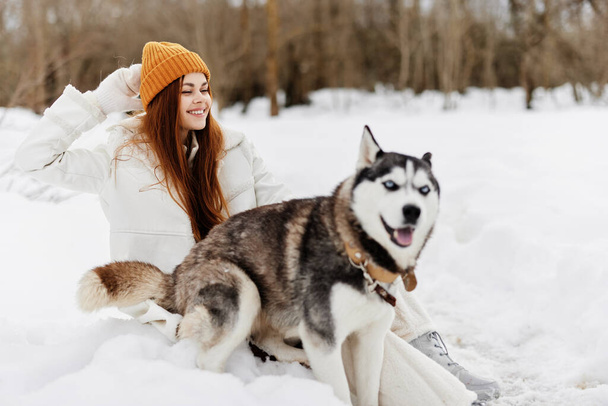 Gelukkig jong vrouw buiten in een veld in de winter wandelen met een hond Lifestyle - Foto, afbeelding