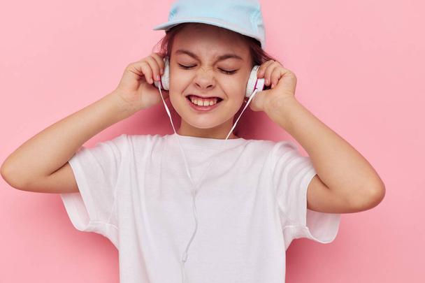 little girl listening to music on headphones isolated background - Foto, Imagem