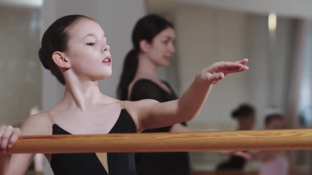Bastante elegante niña entrenamiento ballet con grupo de otras chicas en el estudio - Metraje, vídeo