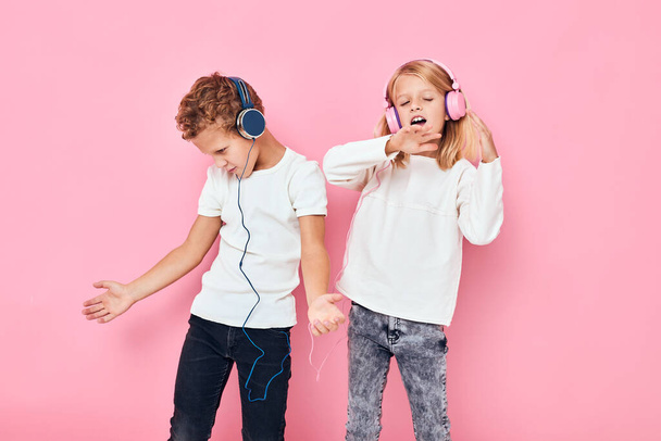 Stylish little boy and cute girl dancing with headphones entertainment pink color background - Photo, image