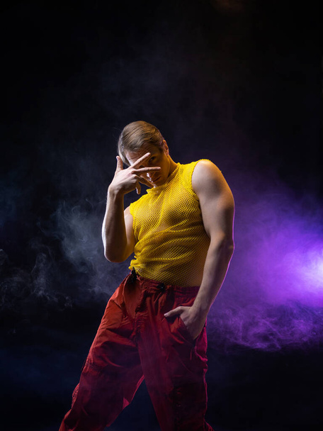 a young muscular man in a bright outfit poses in a pretentious pose, style - Photo, Image