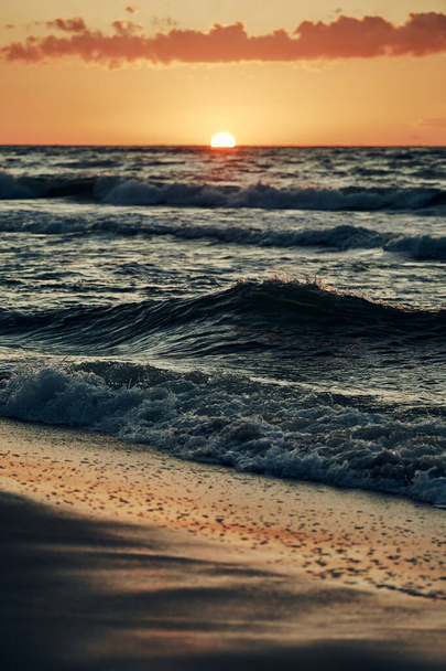 Hermosa puesta de sol sobre las olas del mar, medio sol debajo del horizonte, vista al mar. Olas azules del mar en la luz solar atmosférica en el cielo del atardecer, vacaciones cálidas del verano en el mar, paisaje marino asombroso - Foto, Imagen
